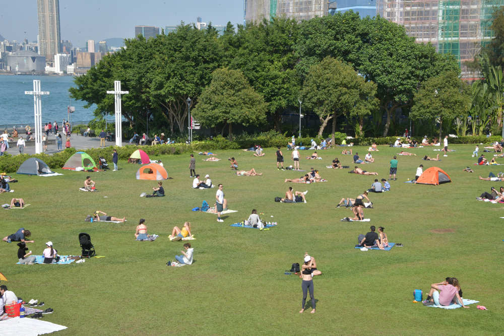 People having fun playing football and grown-ups chilling and chatting on the grassland