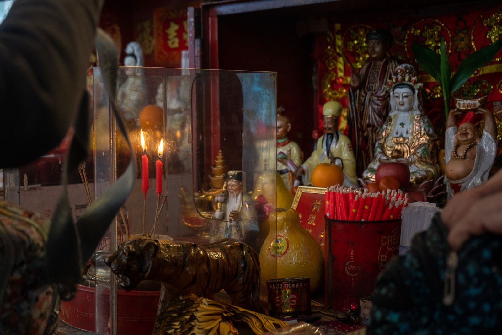 Different Chinese gods like the Happy Buddha and the Goddess of Mercy in a colorful shrine full of incense.
